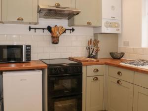 a kitchen with a stove and a microwave at Hope Cottage in Hambleton