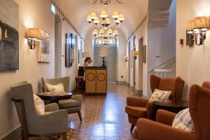 a lobby with chairs and tables and a woman in the distance at Soho House Tel Aviv in Tel Aviv