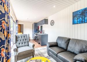 a living room with a couch and a kitchen at Woodland Lakes Boutique Lodges 