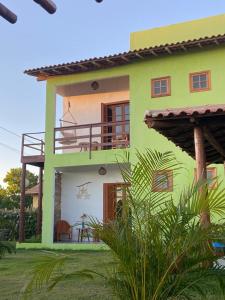 een groen en wit huis met een balkon bij Pousada TAUANE in Caraíva