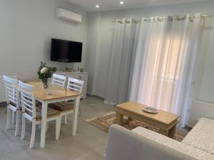 una sala da pranzo con tavolo, sedie e TV di Mimozas Apartment Porto Heli a Porto Heli