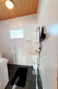 ein Bad mit einem Waschbecken, einem WC und einem Fenster in der Unterkunft Saunatupa in Syöte