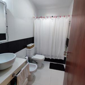 Baño blanco con aseo y lavamanos en Casa en Solares del Carcaraña en Oliveros