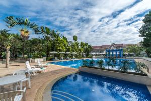 una piscina en un complejo con mesas y sillas en Somerset Vientiane, en Vientiane