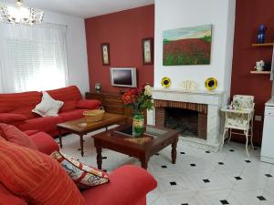 sala de estar con muebles de color rojo y chimenea en CASA RURAL EL ROCINANTE, en Miguel Esteban