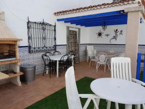 a patio with white tables and chairs and a fireplace at CASA RURAL EL ROCINANTE in Miguel Esteban