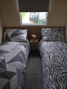 two beds in a small room with a window at A22 is a 3 bedroom caravan on Whitehouse Leisure Park in Towyn near Abergele with decking and close to sandy beach in Conwy