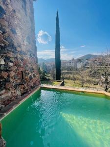 a swimming pool in front of a stone wall at Hotel Cal Sastre in Santa Pau