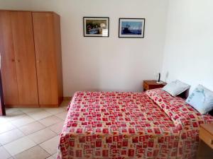a bedroom with a bed with a red and white bedspread at Apartments Martinac in Sukošan