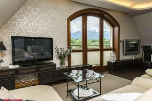 a living room with a television and a couch at Apartament De Lux Cicha Woda in Zakopane