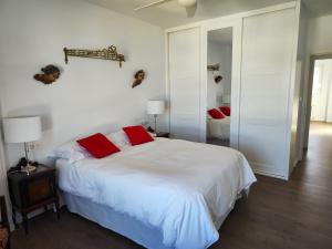1 dormitorio con 1 cama blanca grande con almohadas rojas en ENTREOLIVOS, en Jaén