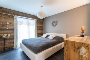 1 dormitorio con 1 cama y pared de madera en Appartement Rosalp, 200m des télécabines,, en Nendaz