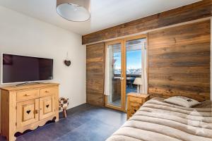 a bedroom with a bed and a flat screen tv at Appartement Rosalp, 200m des télécabines, in Nendaz