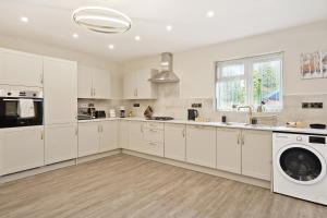 eine Küche mit weißen Schränken, einer Waschmaschine und einem Trockner in der Unterkunft Luxurious 4 Bed House, Solihull, NEC, Airport, Business & Leisure Stays - Wisteria House in Solihull