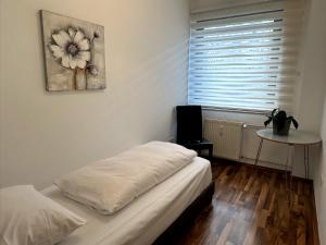 a bedroom with a bed and a window with a flower painting at Willy Studio Apartment Frankfurt in Frankfurt/Main