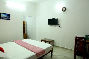 a bedroom with a bed and a tv on the wall at THEKKADY HOMES in Thekkady