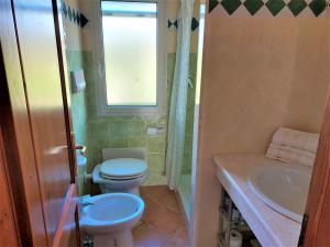 a bathroom with a toilet and a sink and a window at Appartamenti Sisula Manna in Orosei