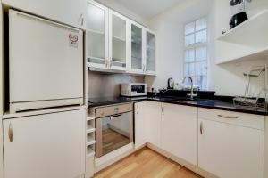 een keuken met witte kasten en een roestvrijstalen koelkast bij The Quebec Residence in Londen
