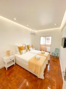 a white bedroom with a large bed and a tv at So Sweet Center of Faro Flat in Faro