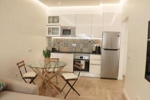 a kitchen with a glass table and a refrigerator at So Sweet Center of Faro Flat in Faro