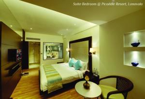 a hotel room with a bed and a table and chair at Meritas Picaddle Resort Lonavala in Lonavala