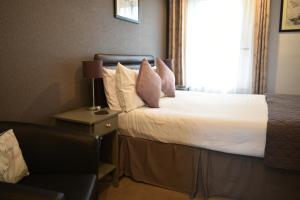 a bedroom with a bed with white sheets and pink pillows at Taunton House in Great Yarmouth