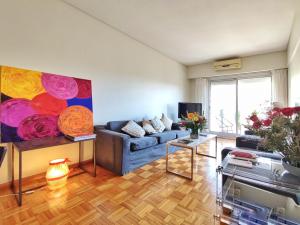una sala de estar con un sofá azul y una pintura en Alquiler Departamento Temporario de 3 Ambientes, Quintana al 500, Recoleta. en Buenos Aires