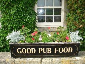 una buena señal de comida de pub delante de una ventana en Inn for All Seasons, en Burford