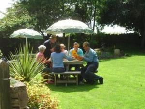 a group of people sitting at a picnic table under an umbrella at Inn for All Seasons in Burford