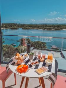 a table with food on it with a view of the water at Suítes Luxo Marambaia- Epic House in Rio de Janeiro