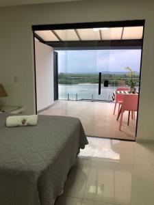 a bedroom with a bed and a view of a table at Suítes Luxo Marambaia- Epic House in Rio de Janeiro