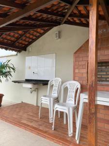 2 sedie bianche sedute su un patio con cucina di Pousada Vilas Boas a Barreirinhas