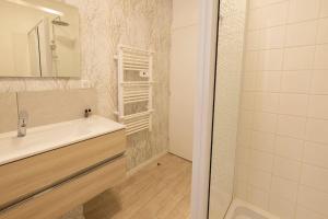 een badkamer met een witte wastafel en een douche bij Le Cosy C - T2 Tout Équipé - Centre-Ville Gare in Montluçon