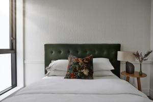 a bedroom with a large bed with a green headboard at Cloud Loft Residence with 180 Degrees Views in Auckland