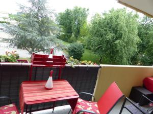 a patio with a red table and chairs on a balcony at Appartement cosy 4 personnes in Mâcon