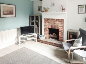 a living room with a fireplace and a television at Post Cottage in Hulland