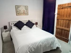 a bedroom with a white bed with two blue pillows at Post Cottage in Hulland