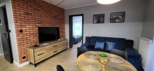 sala de estar con sofá, mesa y TV en Apartamenty Nord en Darlowko