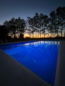 una piscina azul por la noche con árboles en el fondo en CABAÑAS DON GENARO en Bella Vista