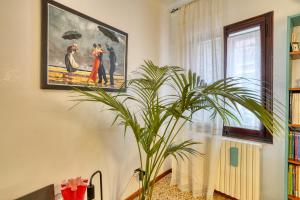 a painting hanging on a wall next to a plant at Biennale Venice Charme Apartment in Venice