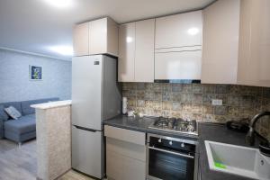 a kitchen with white cabinets and a refrigerator at Ninia's Apartment in Kutaisi