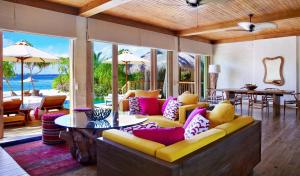 a living room with a yellow couch and colorful pillows at Six Senses Laamu in Laamu Atoll