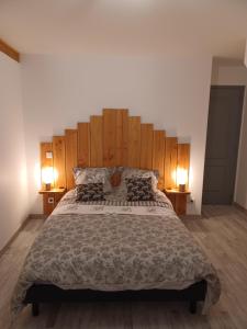 a bedroom with a large bed with a wooden headboard at la maison du bonheur in Saint-Germain-Laval