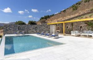 a swimming pool with chairs and a building at Falcon Villa in Chavgas