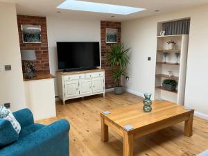 a living room with a television and a table at Honeyberry Cottage -PART OF ALTON COTTAGES in Alton