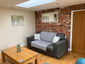 a living room with a couch and a brick wall at Honeyberry Cottage -PART OF ALTON COTTAGES in Alton