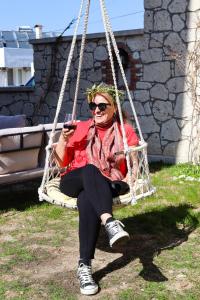 a woman sitting in a swing looking at her cell phone at Siriusmi Hotel in Çeşme