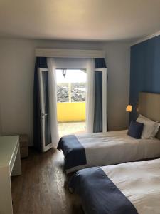 a hotel room with two beds and a window at Vinha da Areia Beach Hotel in Vila Franca do Campo