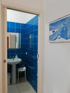 La salle de bains est pourvue de carrelage bleu, d'un lavabo et d'un miroir. dans l'établissement Casette Santini B&B, à Casalbordino