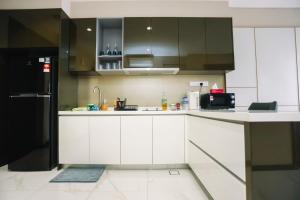 uma cozinha com armários brancos e um frigorífico preto em Apartment in Bukit Bintang with a clear KLCC view em Kuala Lumpur